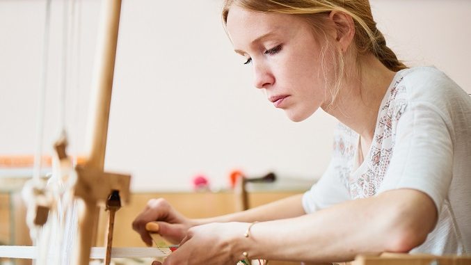 The girl in the production process of textiles are handmade on a loom